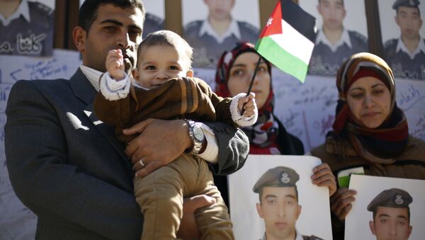 Familiares do piloto jordaniano executado pelo Estado Islâmico seguram cartazes com seu retrato - Sputnik Brasil
