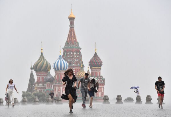 Pessoas caminham pela Praça Vermelha, em Moscou, enquanto chove - Sputnik Brasil