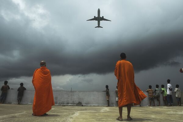 No topo de um edifício budista, monges observam avião decolando do Aeroporto Internacional Netaji Subhash Chandra Bose, enquanto autoridades indianas relaxam medidas adotadas para combater a proliferação do coronavírus - Sputnik Brasil
