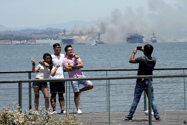 Pessoas tiram fotos próximas a incêndio do navio de assalto anfíbio USS Bonhomme Richard, no estado norte-americano da Califórnia - Sputnik Brasil