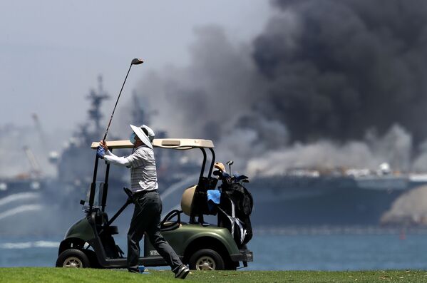Homem passeia em campo de golfe enquanto navio anfíbio USS Bonhomme Richard enfrenta incêndio em base da Marinha dos EUA - Sputnik Brasil