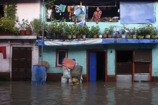 Mulher olha para rua durante enchente do rio Bagmati após fortes chuvas na capital do Nepal, Catmandu - Sputnik Brasil