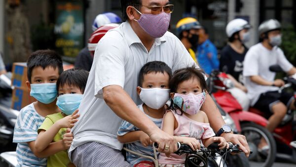 Homem e crianças, com máscaras protetoras, andam de bicicleta na rua em meio à pandemia do coronavírus, em Hanói, Vietnã, 27 de julho de 2020 - Sputnik Brasil