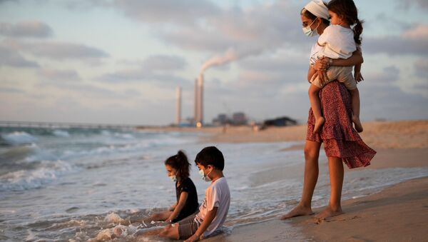 Crianças usando máscaras brincam na água ao longo da costa do mar Mediterrâneo - Sputnik Brasil