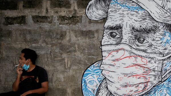 Homem fumando junto de mural de pessoa com máscara - Sputnik Brasil