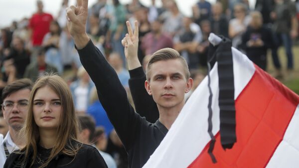 Pessoas seguram bandeira diante de multidão em protesto em Minsk, na Bielorrússia - Sputnik Brasil