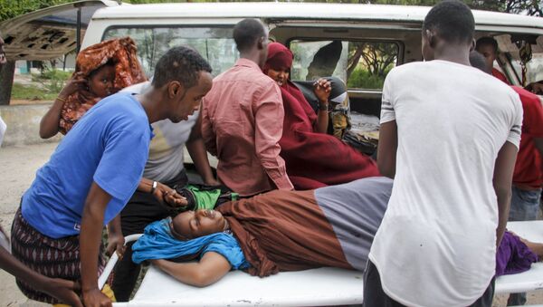 Médicos e civis ajudam a carregar mulher ferida em ataque com carro-bomba em hotel em Mogadíscio, na Somália. Ato foi reivindicado pelo grupo Al-Shabaab - Sputnik Brasil