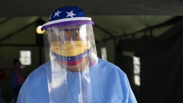 Mulher com roupa de proteção e máscara com bandeira da Venezuela administra testes para coronavírus em Caracas - Sputnik Brasil