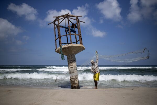 Um pescador palestino limpa sua rede de pesca em uma praia na cidade de Gaza - Sputnik Brasil