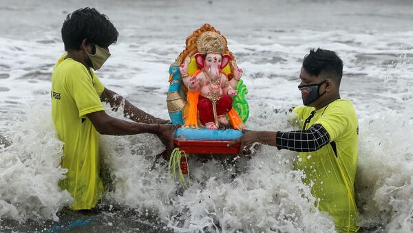 Jovens de máscaras para se proteger do coronavírus carregam estátua do deus Ganesh em Mumbai, na Índia - Sputnik Brasil
