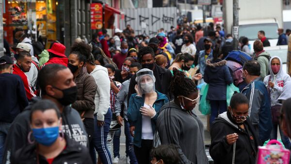 Mulher usando máscara a protetor facial contra coronavírus fala no celular em rua movimentada de São Paulo - Sputnik Brasil