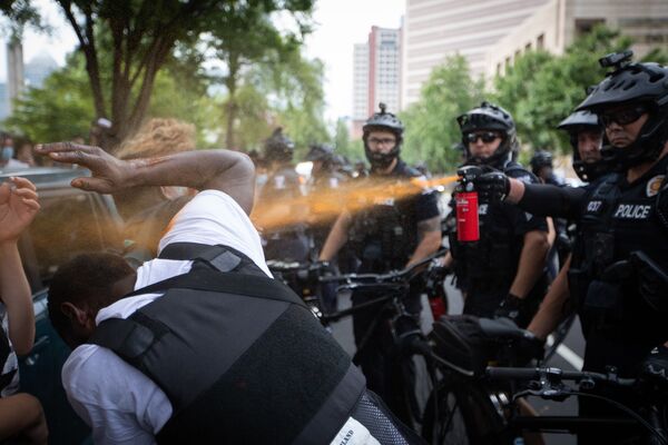 Polícia lança gás sobre um manifestante durante protestos em Charlotte, EUA - Sputnik Brasil