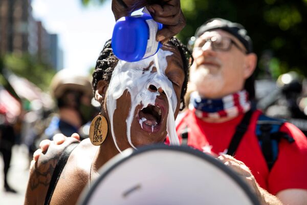 Manifestantes lavam olhos de uma mulher com leite durante protestos em Portland, EUA - Sputnik Brasil