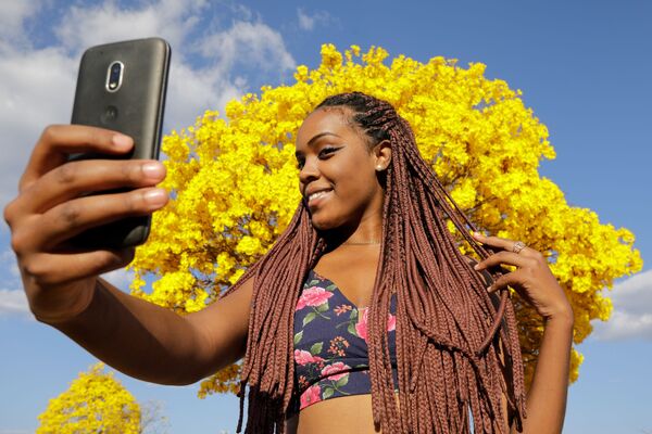 Mulher posa para selfie em frente a árvore ipê-amarelo em Brasília - Sputnik Brasil