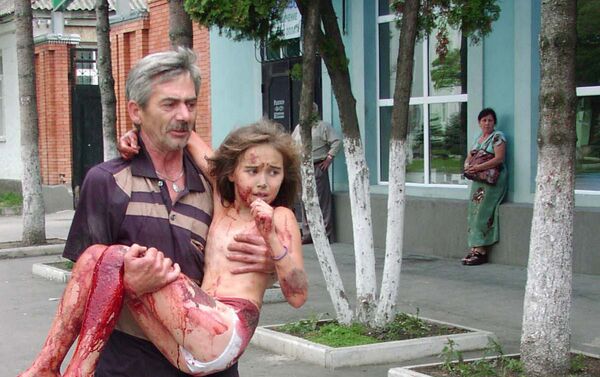 Morador da cidade de Beslan carrega menina feita refém durante ato terrorista para fora da área da escola, Beslan, Rússia, 4 de setembro de 2004 - Sputnik Brasil
