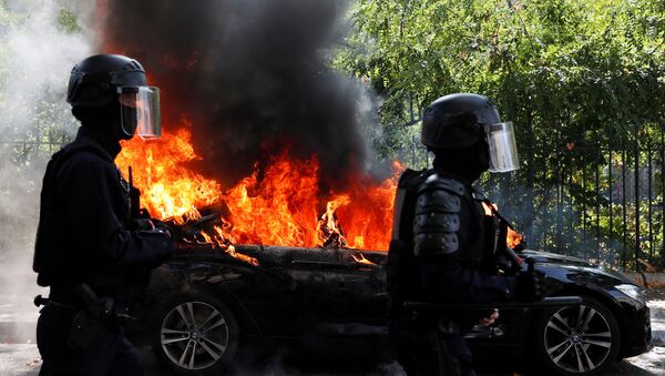 Em Paris, policiais passam em frente a um carro em chamas em meio aos protestos dos coletes amarelos, em 12 de setembro de 2020. - Sputnik Brasil