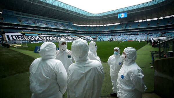Funcionários usam roupa protetora contra coronavírus na Arena do Grêmio, antes do jogo entre Grêmio e Fortaleza - Sputnik Brasil
