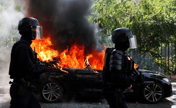 Policiais franceses passam por um carro em chamas durante um protesto dos Coletes Amarelos em Paris
 - Sputnik Brasil