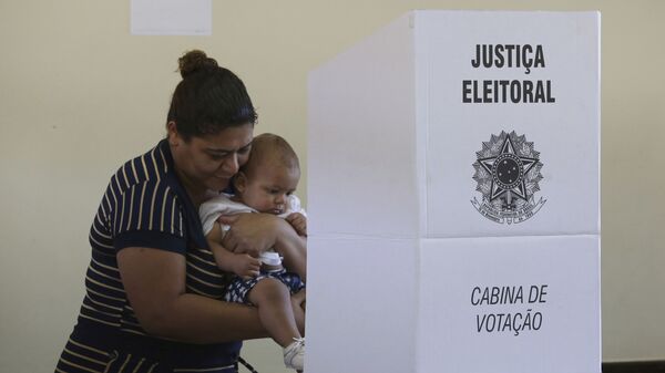 Em Brasília, mulher com bebê nos braços vota em urna eletrônica, durante as eleições gerais no Brasil, em 28 de outubro de 2018 - Sputnik Brasil