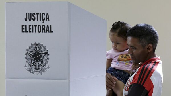 Em Brasília, um homem com um bebê nos braços deposita seu voto em uma urna eletrônica durante as eleições gerais no Brasil, em 28 de outubro de 2018. - Sputnik Brasil