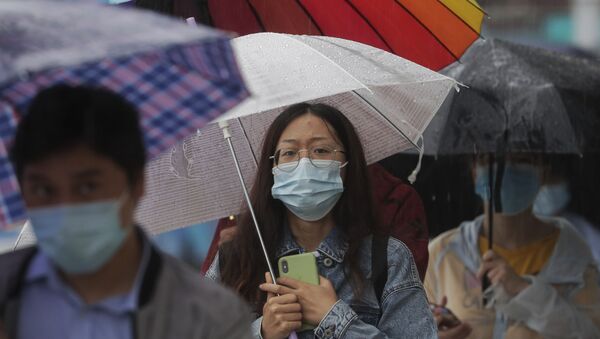 Pessoas caminham com máscaras enquanto chove na China - Sputnik Brasil