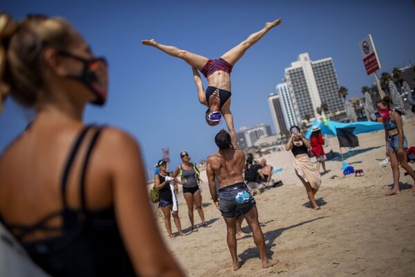 Acrobatas executam truque durante um protesto contra a decisão de fechar as praias por causa da pandemia de coronavírus em Tel Aviv, Israel - Sputnik Brasil
