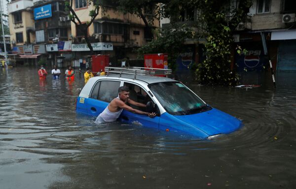 Homem empurra um táxi em rua inundada após chuva torrencial em Mumbai, Índia
 - Sputnik Brasil