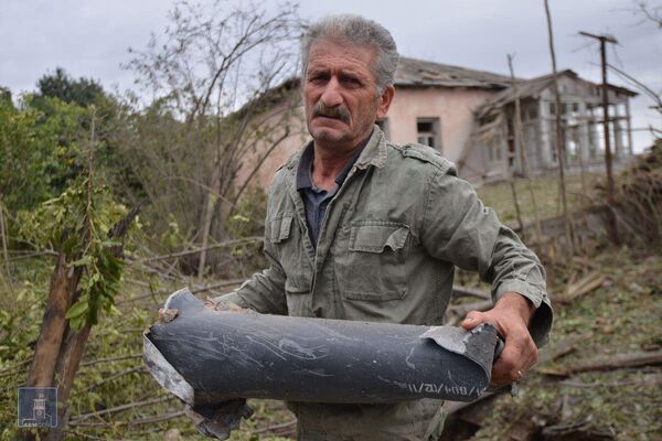Homem segura estilhaço de munição após bombardeio por forças azeris na cidade de Martuni, em Nagorno-Karabakh - Sputnik Brasil