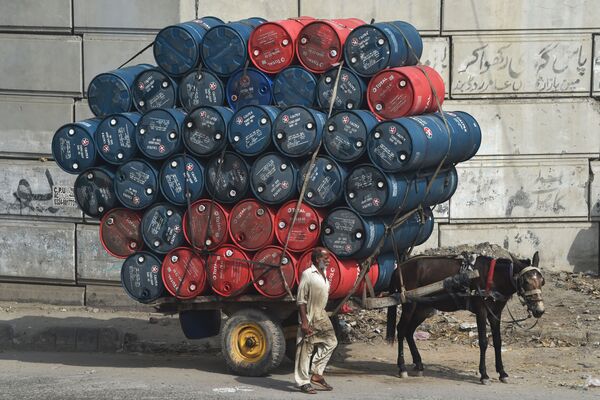 Homem passa ao lado de cavalo e carroça carregada com barris, no Paquistão - Sputnik Brasil