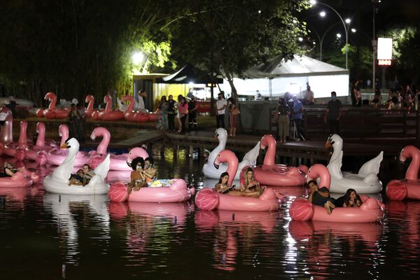 Pessoas relaxando em flamingos e cisnes infláveis, no Parque da Cidade Sarah Kubitschek, assistindo a um filme no decorrer do Festival Flutua, o primeiro festival flutuante do país, em Brasília, 30 de setembro de 2020 - Sputnik Brasil