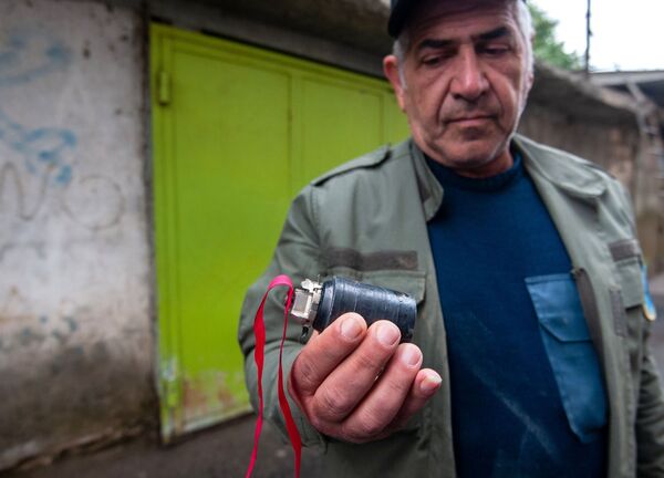 Homem segura submunição de fragmentação utilizada em ataques contra a cidade de Stepanakert, em Nagorno-Karabakh - Sputnik Brasil