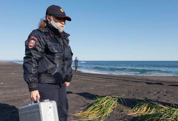Policial passa por praia enquanto ocorre a coleta de amostras do incidente em Kamchatka, na Rússia - Sputnik Brasil