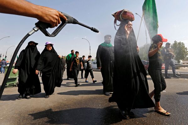 Peregrinos muçulmanos xiitas iraquianos são pulverizados com água para esfriar enquanto caminham à cidade sagrada de Kerbala
 - Sputnik Brasil