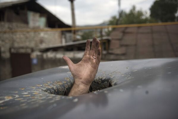 Mão se estende através de buraco deixado em carro por bombardeio à cidade de Stepanakert, em Nagorno-Karabakh - Sputnik Brasil
