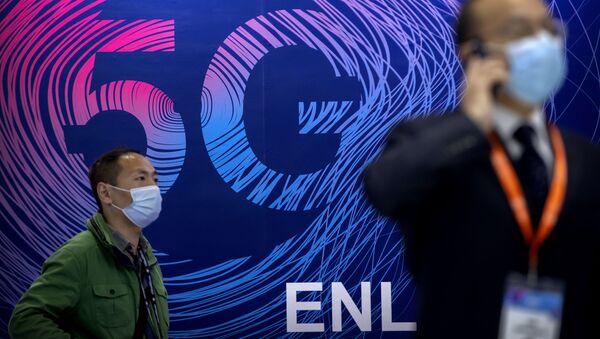 Em Pequim, na China, um homem usando máscara para proteger-se da COVID-19 passa em frente a uma propaganda da tecnologia 5G durante uma exposição, em 14 de outubro de 2020 - Sputnik Brasil