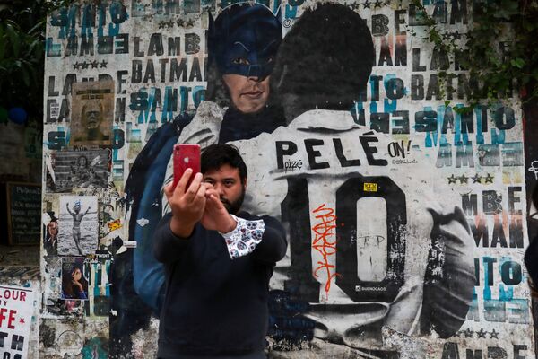 Homem tira selfie perto de um mural que retrata a lenda do futebol brasileiro Pelé
 - Sputnik Brasil