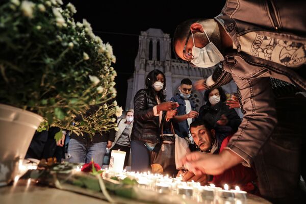 Pessoas acendem velas fora da Basílica Notre-Dame de Assunção em Nice, 29 de outubro de 2020, em memória de três vítimas do atacante com faca, que cortou a garganta de pelo menos uma mulher no interior da igreja, na cidade da Riviera Francesa - Sputnik Brasil