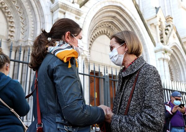 Duas mulheres seguram as mãos em frente à Basílica de Notre-Dame em Nice, em 30 de outubro de 2020, durante uma homenagem às vítimas mortais do atacante com faca no dia anterior - Sputnik Brasil