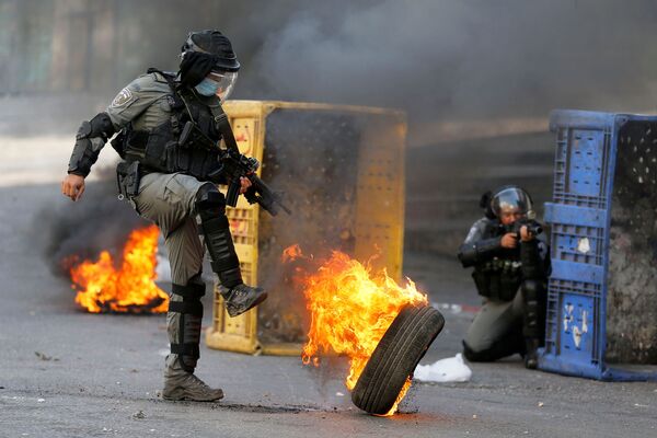 Policial de fronteira israelense chuta pneu em chamas durante protesto contra Israel promovido por palestinos em Hebron, na Cisjordânia - Sputnik Brasil