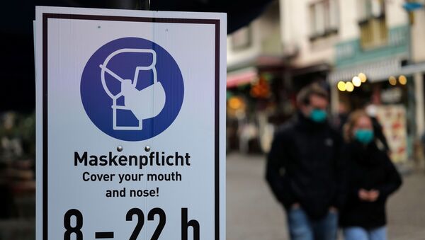 Em Frankfurt, pessoas usam máscaras enquanto caminham ao lado de uma placa pedindo que as pessoas cubram seus narizes e bocas em meio à pandemia da COVID-19, em 27 de outubro de 2020 - Sputnik Brasil