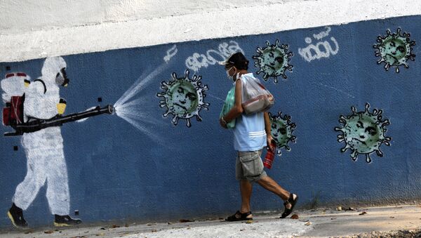 Um homem caminha ao lado de um grafite retratando um limpador em equipamento de proteção espalhando vírus com o rosto do presidente Jair Bolsonaro, em meio ao surto da doença coronavírus (COVID-19), no Rio de Janeiro, Brasil, 7 de outubro de 2020 - Sputnik Brasil