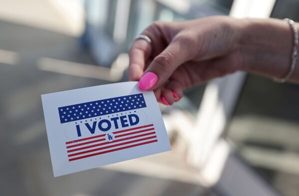 Pessoa exibe etiqueta Eu votei, enquanto cidadãos votam nas eleições do presidente dos EUA no primeiro dia de votação presencial alargada em meio à pandemia da COVID-19, em Los Angeles, Califórnia, EUA, 30 de outubro de 2020 - Sputnik Brasil