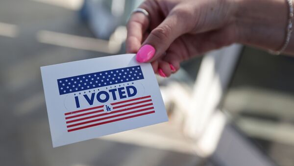 Pessoa exibe etiqueta Eu votei, enquanto cidadãos votam nas eleições do presidente dos EUA no primeiro dia de votação presencial alargada em meio à pandemia da COVID-19, em Los Angeles, Califórnia, EUA, 30 de outubro de 2020 - Sputnik Brasil