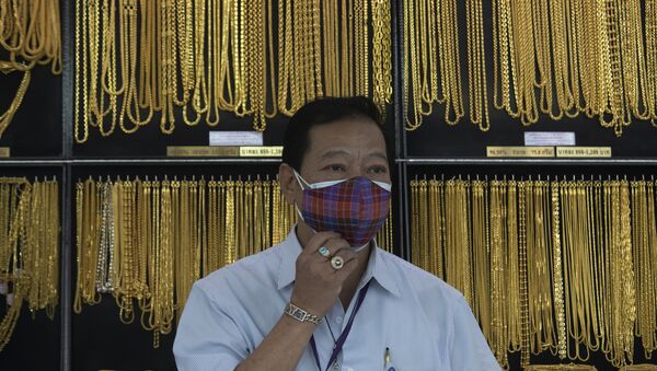Vendedor na Tailândia usando máscara contra a COVID-19 diante de artigos de ouro - Sputnik Brasil
