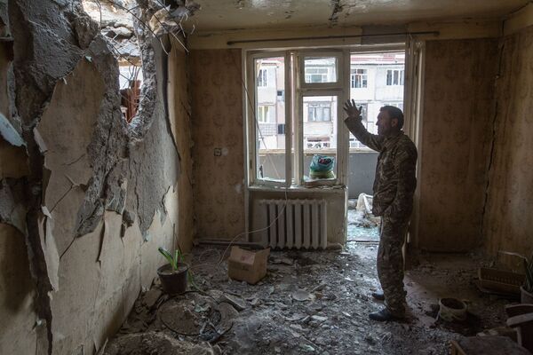 Homem é fotografado em um apartamento em ruínas em Stepanakert, Nagorno-Karabakh, enquanto região vive conflito armado entre azeris e armênios - Sputnik Brasil