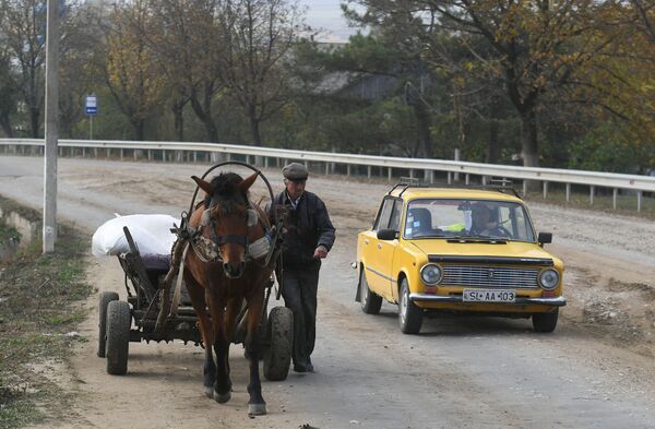 Homem segue caminho ao lado de uma carroça enquanto um veículo passa a seu lado no vilarejo Plop-Stiubei na Moldávia - Sputnik Brasil