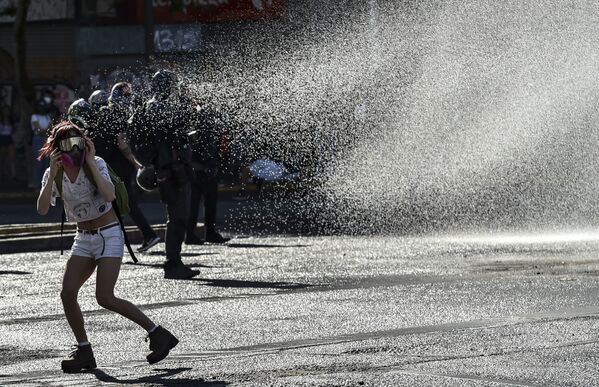 Manifestantes recebem jatos de canhão de água da polícia durante ato contra o presidente chileno Sebastián Piñera em Santiago, Chile - Sputnik Brasil