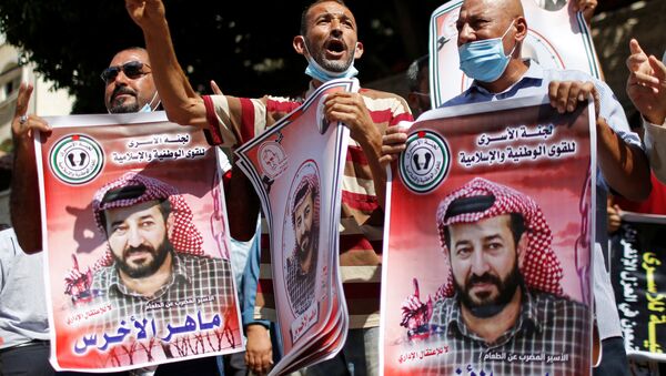 Manifestantes seguram fotos do prisioneiro palestino em greve de fome Maher Al-Akhras, detido por Israel, durante uma manifestação de solidariedade a Al-Akhras, na cidade de Gaza, em 12 de outubro de 2020. REUTERS / Mohammed Salem - Sputnik Brasil
