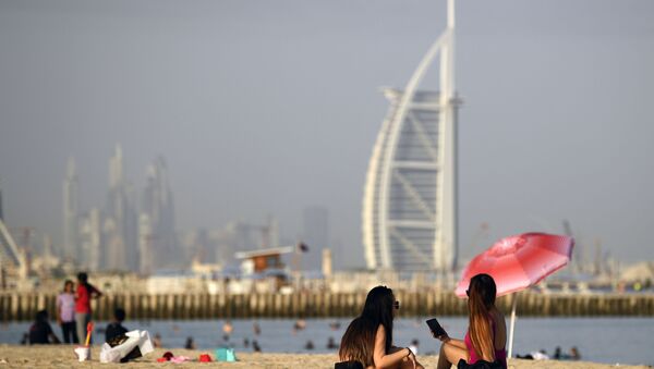Mulheres tomam banho de sol em Dubai, Emirados Árabes Unidos, tendo ao fundo o hotel Burj al-Arab (foto de arquivo) - Sputnik Brasil