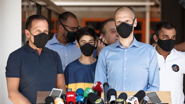 Em São Paulo, o prefeito e candidato à reeleição, Bruno Covas (PSDB) (à frente, à direita), fala ao lado do governador paulista, João Doria (PSDB) (à frente, à esquerda), em frente à zona eleitoral escola Vera Cruz, em 15 de novembro de 2020. Ambos usam máscara contra a COVID-19 - Sputnik Brasil